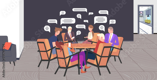 businesspeople sitting at round table chatting during meeting social network chat bubble communication concept business people messaging on smartphones full length horizontal vector illustration