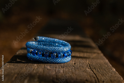 Beautiful, shiny, color bracelet with large beadwork beads. On a wooden bench in the park.