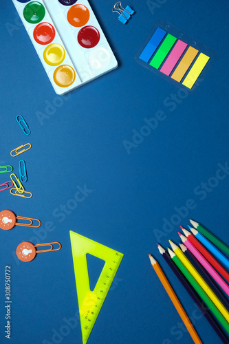 Round frame with colorful pencils scissors on blue background, back to school concept