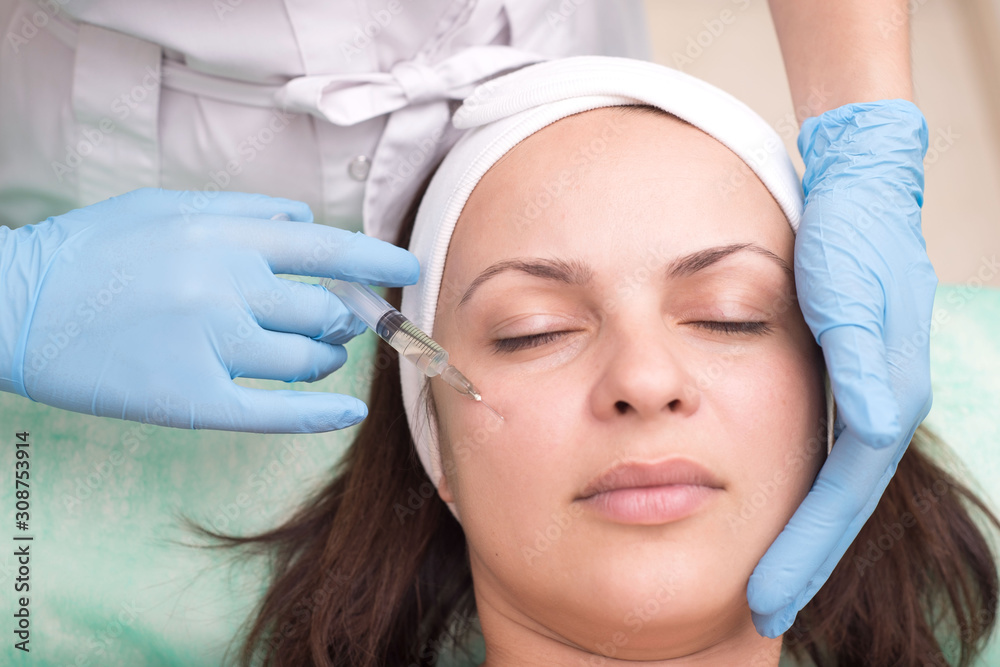 injection into the skin of the face of a young woman, close up. Doctor cosmetologist using a syringe with a needle, injects a remedy for facial wrinkles injection into the skin of the face of a young woman, close up. Doctor cosmetologist using a syringe with a needle, injects a remedy for facial wrinkles
