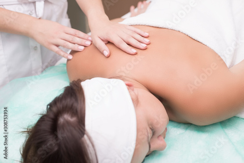 hands of a masseur girl, close up doing back massage to a young woman, in a spa salon