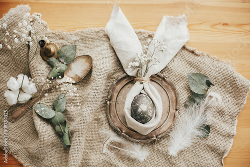 Photography Stylish Easter brunch table setting with egg in easter bunny napkin