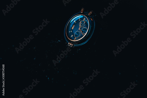 A metallic gold Blue men's watch on a black background. 