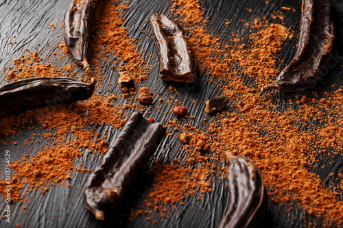 Tableau sur toile Carob carob fruit with powder on black background