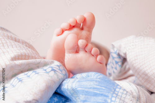 Close up feet of little child girl under the blanket on her bed on bedroom. Sleep and relax concept.