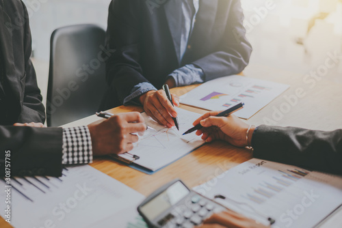 Fotografi Business people gather to analyze marketing and investment information and using pen pointing to financial data chart at meeting
