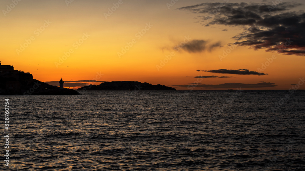 Panoramic view of the Marseille harbour during the sunset with the old lighthouse on the dark background and Mediterranean sea on a foreground. France 2019.