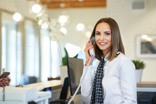 Receptionist answering phone at hotel front desk photo