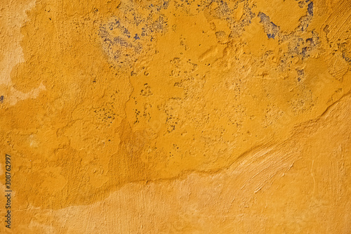 Rough concrete wall painted in yellow color.