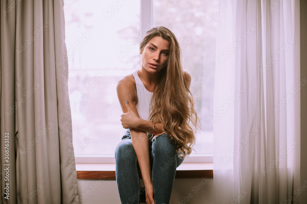 Beautiful young woman sitting by the window Beautiful young woman sitting by the window
