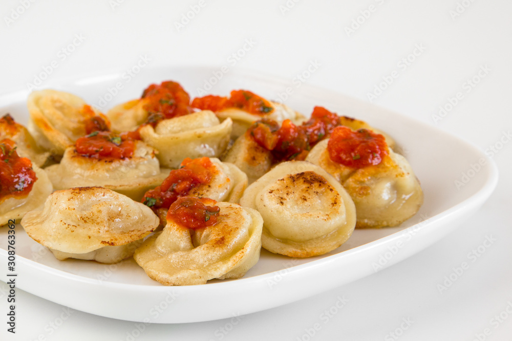 Russian food pelmeni, fried meat dumplings on white plate, with tomato sauce, isolated Russian food pelmeni, fried meat dumplings on white plate, with tomato sauce, isolated