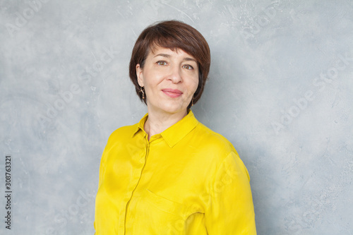 Happy middle aged business woman on gray background, portrait photo