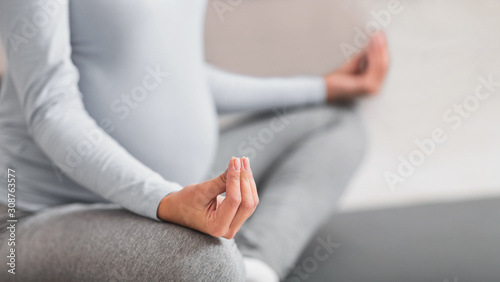 Cropped image of young expectant meditating at home