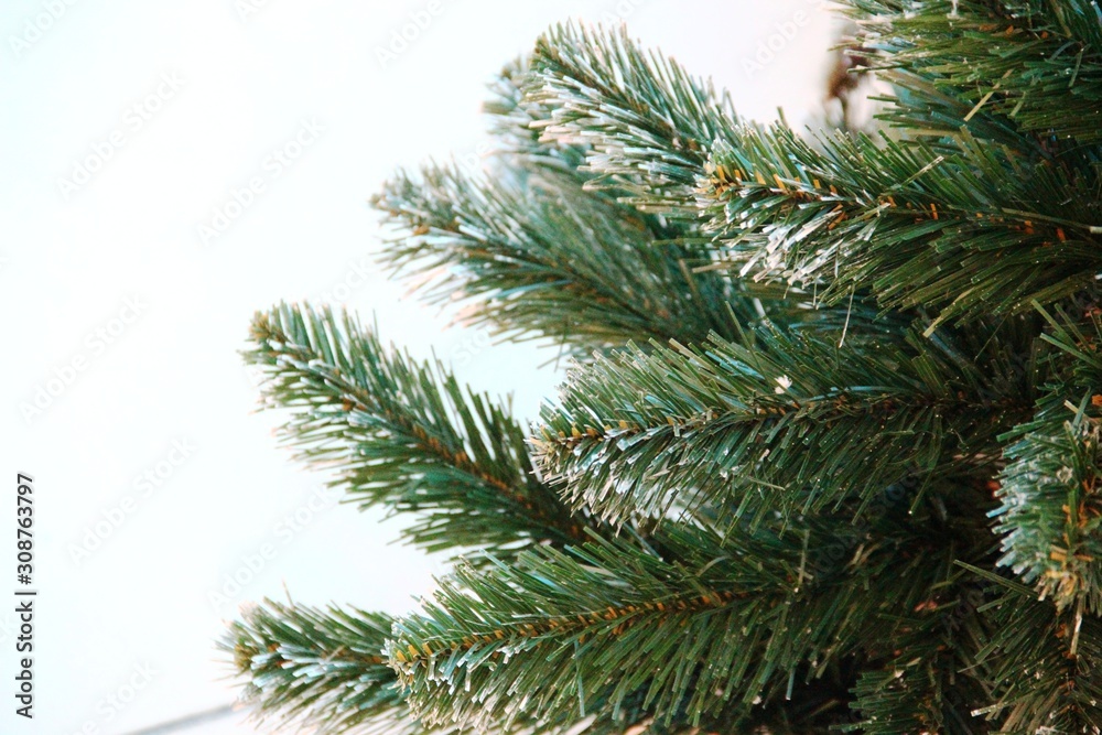 green branches of an artificial Christmas tree. Left place for text, selective focus