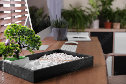 Beautiful miniature zen garden and computer on wooden table in office photo