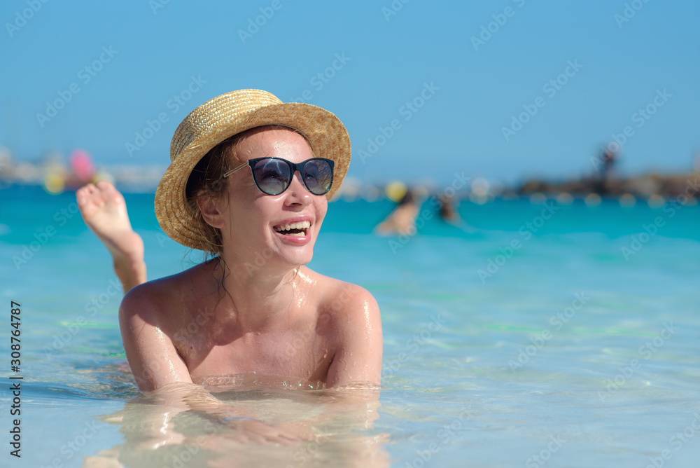Slender European girl in sun hat swimming in ocean during vacations. She relaxing and enjoying her  summer rest.