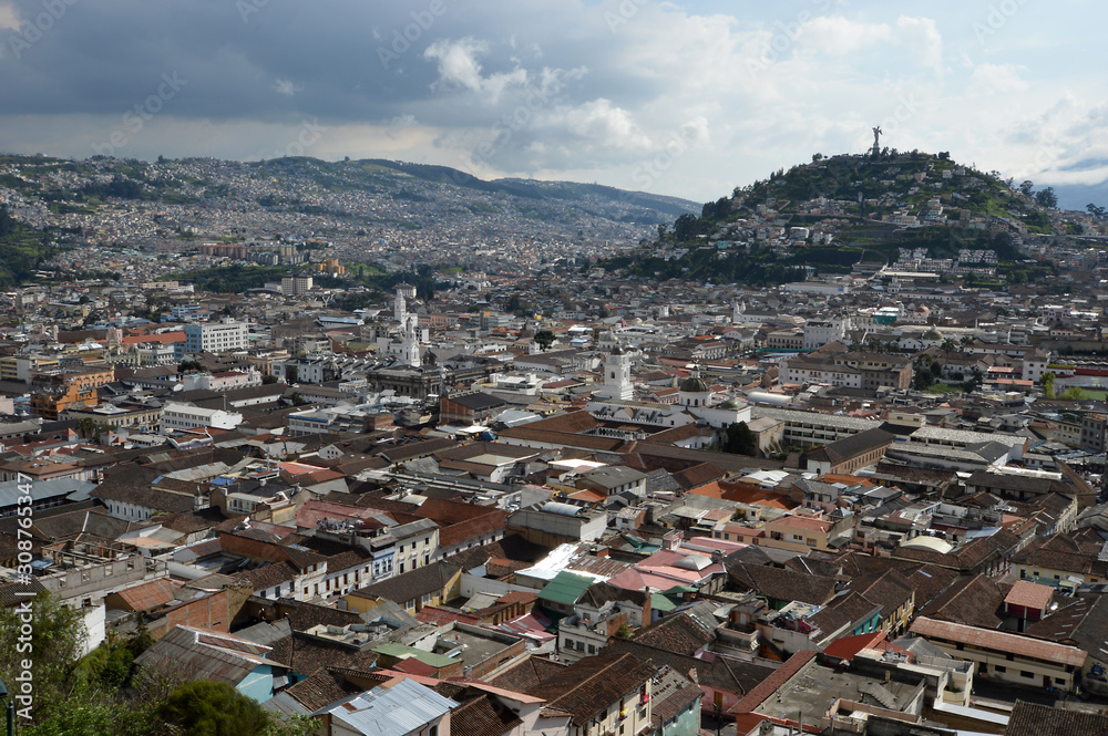 Colonial City of Quito, sunny afternoon on the tile roofs, several temples and ancient churches, in the background the monument to the Virgin on the hill called 