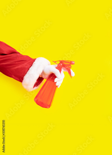 Santa Claus glove hand yellow background spray dispenser one red suit copy space