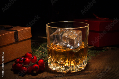 Glass with cognac or whiskey, Gift box and Christmas balls. New Year's tree. Happy holidays decoration.