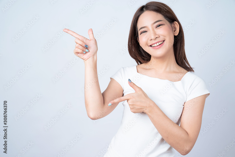 Beautiful young asia stand and pointing to copy space with a cheerful smile on a white background. Beautiful young asia stand and pointing to copy space with a cheerful smile on a white background.