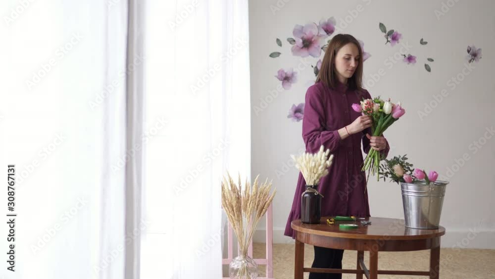 Woman florist makes bouquet of flowers in workshop, slider shot Woman florist makes bouquet of flowers in workshop, slider shot