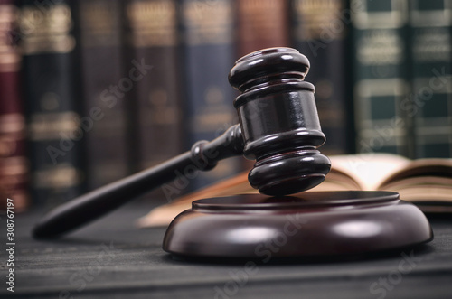Judge Gavel and law book on a black wooden background, law library concept.
