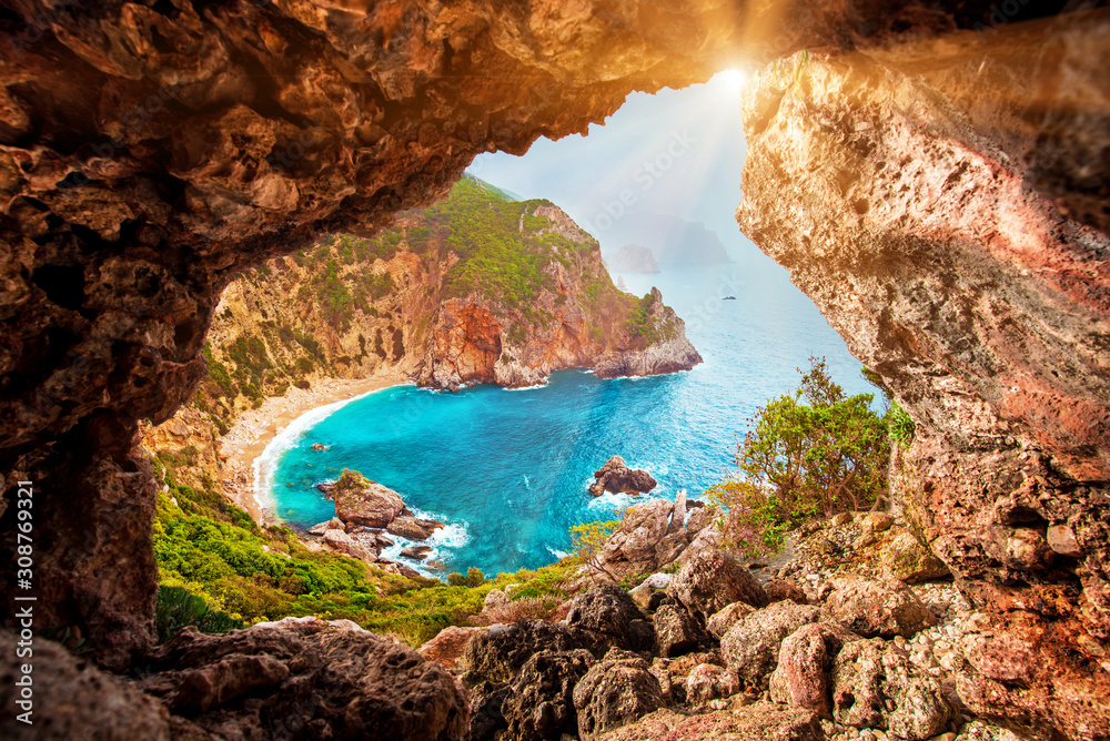 Beautiful magical view of the Gyali beach in Corfu, Greece through a hole in the rock at sunny day. amazing places. popular tourist atraction.