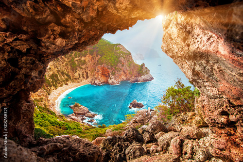 Beautiful magical view of the Gyali beach in Corfu, Greece through a hole in the rock at sunny day. amazing places. popular tourist atraction. photo