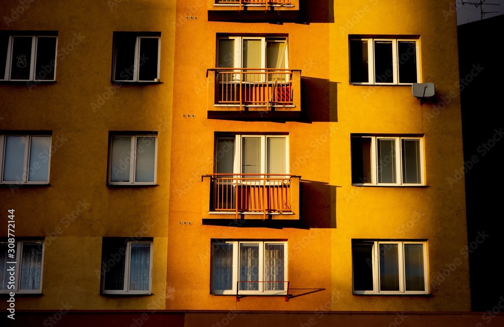 Fototapeta premium Reconstructed block of flats at sunset with sun shining only at one part of the house, the other ones are in shadow