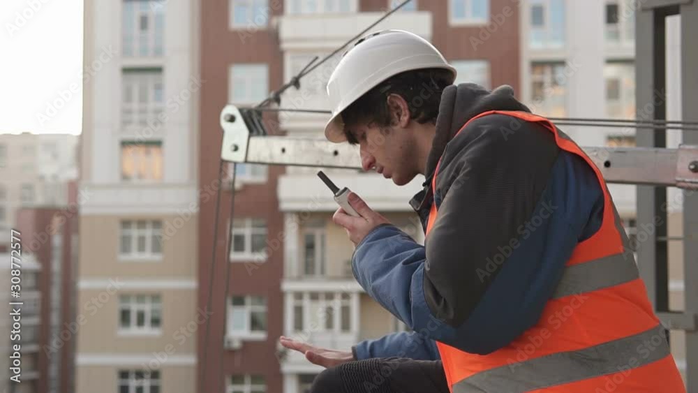 The builder from the roof of the house coordinates the lift using a walkie-talkie The builder from the roof of the house coordinates the lift using a walkie-talkie