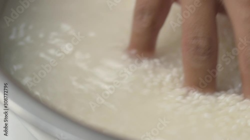 Making Japanese sushi rice, close up hand washing rice in metal bowl.