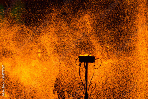 Fire show: black silhouette of a man holding coal equipment in fire sparks