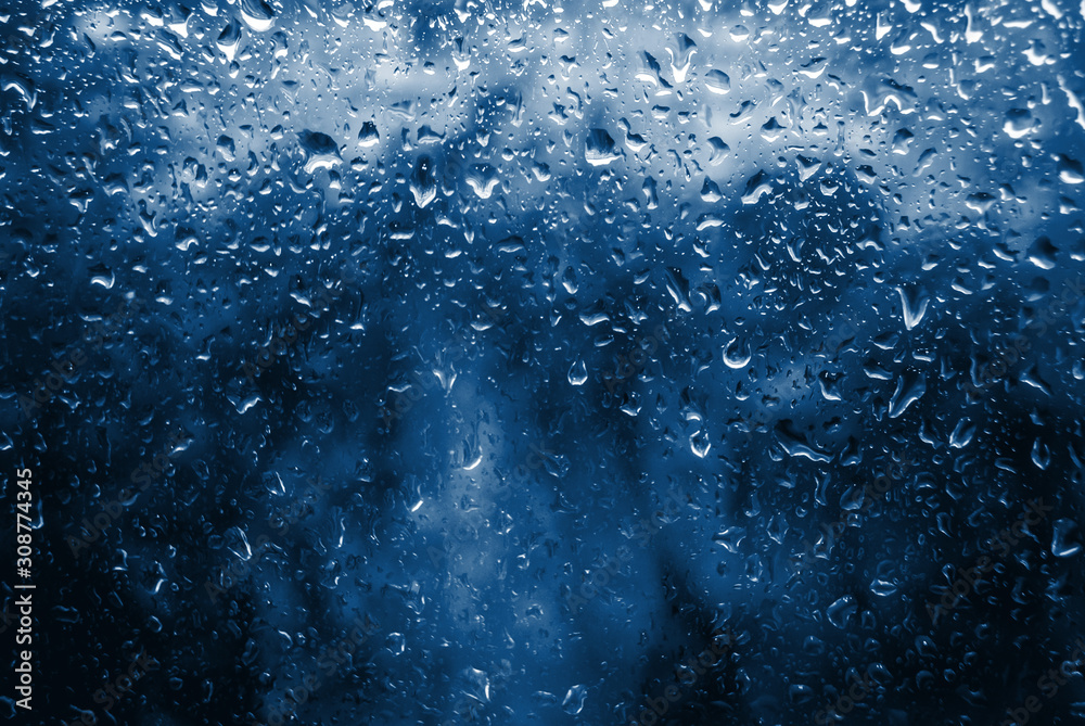 Classic blue toned Spring Rain drops on window and tree in background