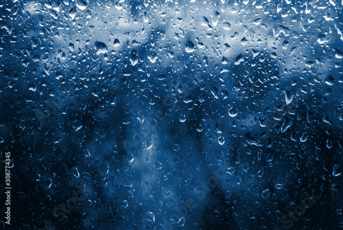 Classic blue toned Spring Rain drops on window and tree in background