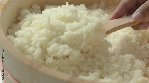 Making Japanese sushi rice, flipping cooked seasoned sushi rice in wood bucket to cool down.