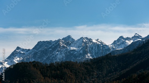 Beautiful autumn forest and mountains covered by snow on background. Krasnaya Polyana, Sochi, Russia.