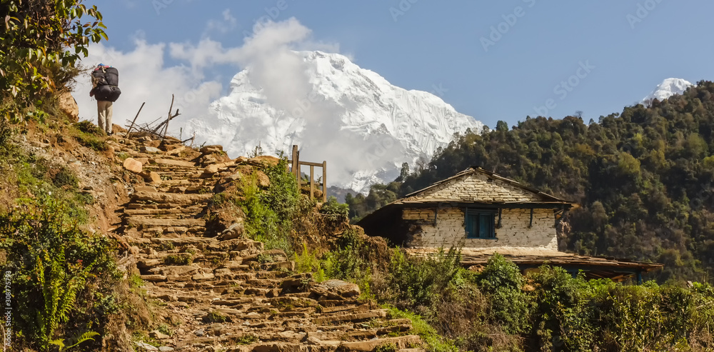 Stone stairs lead up to the Annapurna Base Camp past a traditional rural Nepali house. Stone stairs lead up to the Annapurna Base Camp past a traditional rural Nepali house.