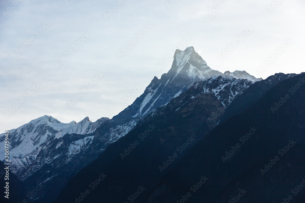 Fototapeta premium A beautiful view of sunlight streaking across the summit of Machapuchare aka the Fishtail mountain seen from the Annapurna Base Camp trail in the Nepal himalaya. 