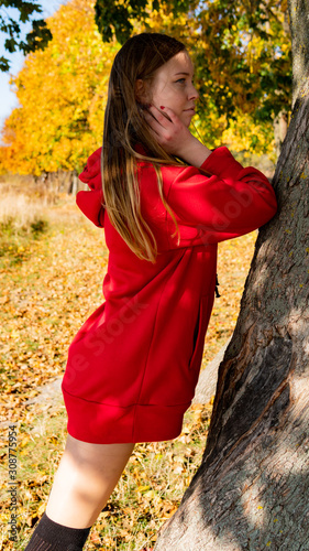 Incredible stunning girl in a red dress. The background is fantastic autumn. Artistic photography.