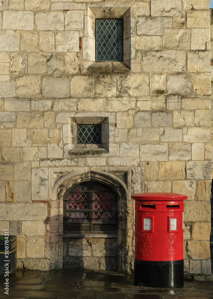 Naklejka premium Red English Postbox against a stone wall