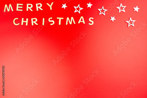 The Inscription Merry Christmas made of wooden letters  lying flat from above  isolated on a red background.