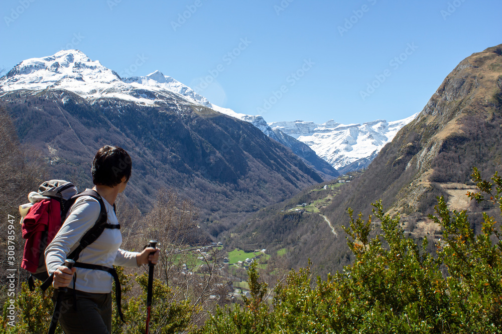 woman hiker admiring the cirque of Gavarnie snow-covered in the distance, the helmet and the breach of Roland