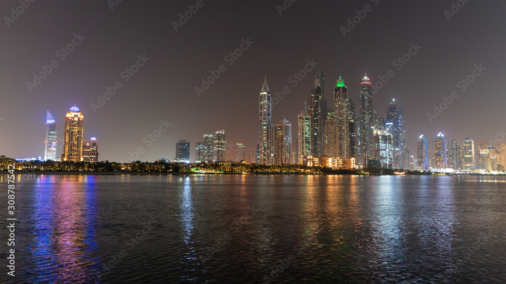 Dubai skyline at night with lights on the water and luxirious skyscrapers of UAE