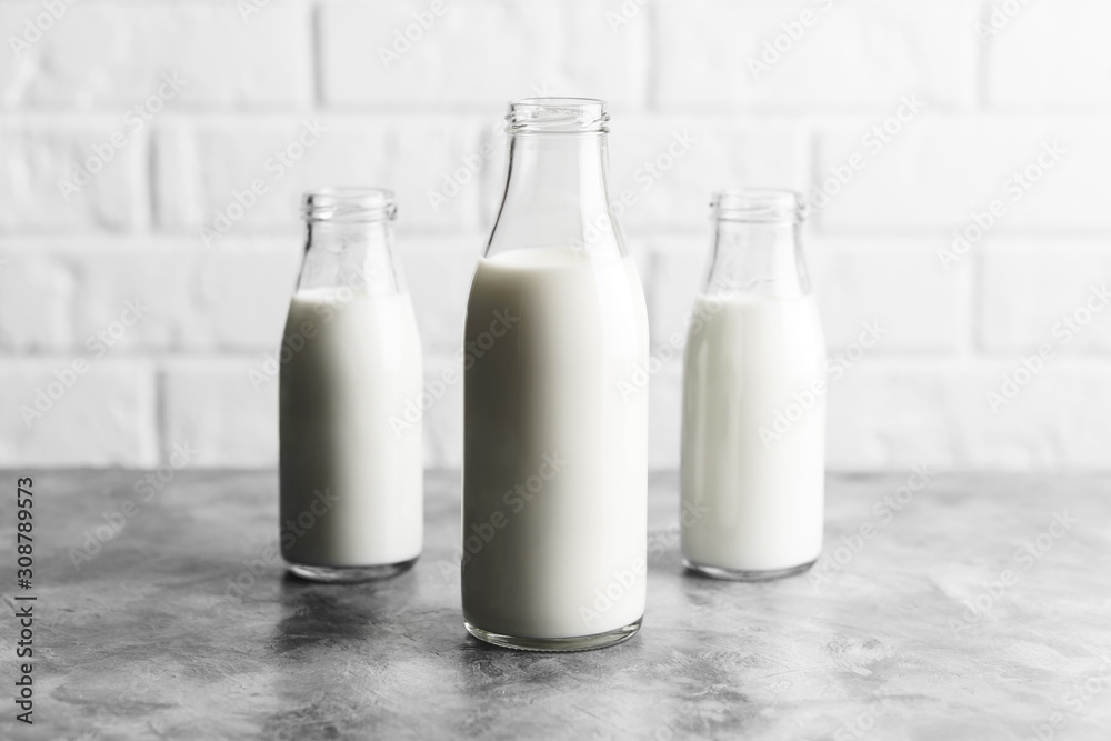 Three glass reusable bottles of milk in the kitchen with marble countertops and a white brick wall. Three glass reusable bottles of milk in the kitchen with marble countertops and a white brick wall.