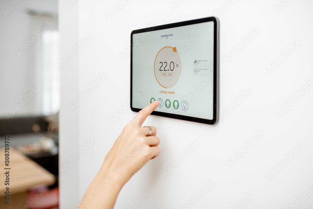 Controlling temperature in the living room with a digital touch screen panel installed on the wall. Concept of heating control in a smart home, close-up on a screen Controlling temperature in the living room with a digital touch screen panel installed on the wall. Concept of heating control in a smart home, close-up on a screen