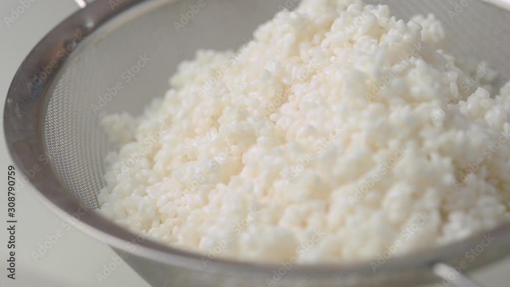Making Japanese sushi rice, straining washed rice in a sieve. Making Japanese sushi rice, straining washed rice in a sieve.