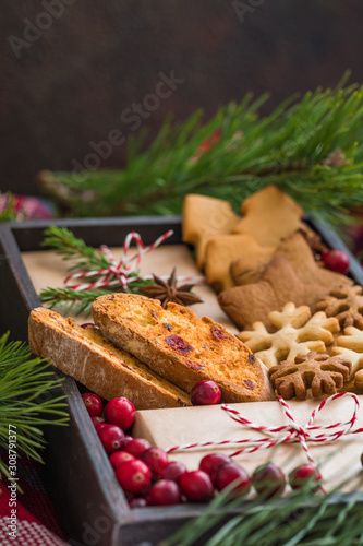 Homemade christmas cookies and wrapped presents with fresh cranberries in a wooden box, close up
