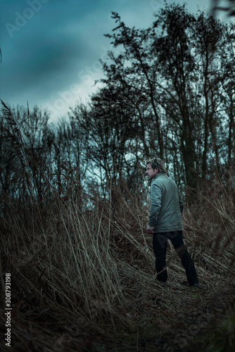 Man in jacket walking between reed in autumn. © ysbrandcosijn