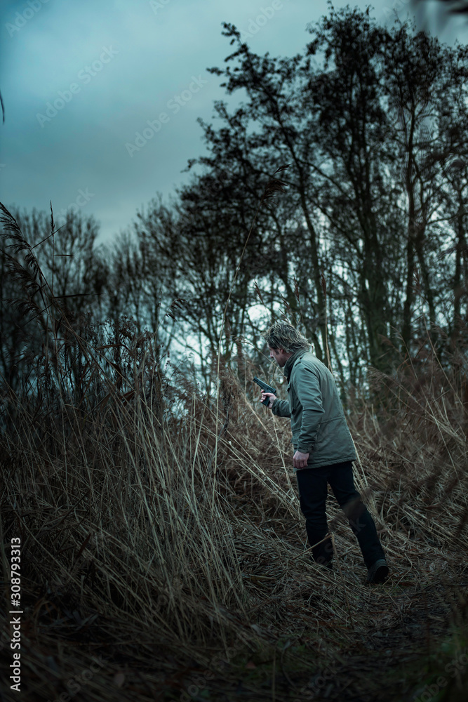 Man with pistol between reed on cloudy day. Man with pistol between reed on cloudy day.