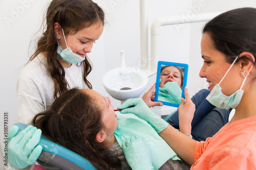 Two little girls in dental surgery with cheerful female dentist